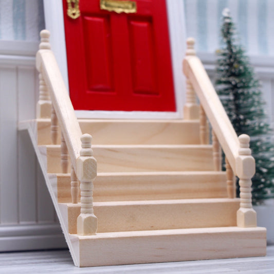Wooden staircase model in front of a red door with a Christmas tree in the background